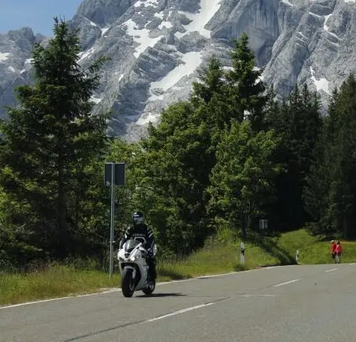 Motorrijder op een bergweg met uitzicht op de bergen tijdens motorreis Alpen en Bergmeren
