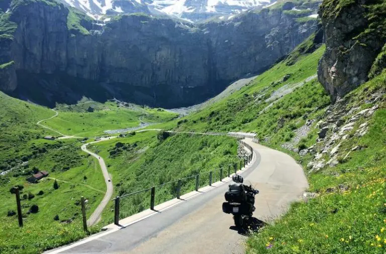Motor op een bergweg door een groene Alpenvallei tijdens motorreis Combi Oostenrijk Zwitserland