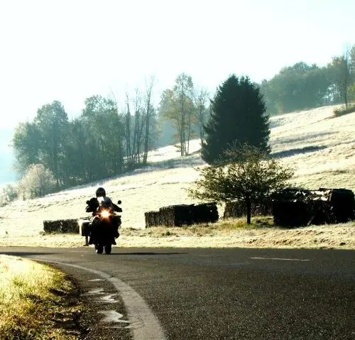 Motorrijder op een landelijke weg in het winterse landschap tijdens motorreis Journey to the Heart of Europe