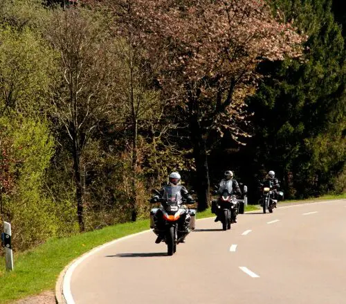 Groep motorrijders op een bochtige weg tijdens motorreis Journey to the Heart of Europe