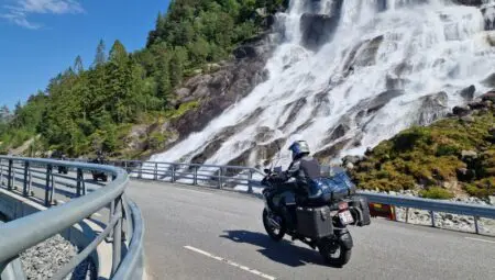 Motorrijder bij waterval tijdens motorreis Norwegian Shortcut, Fjord Norway, Noorwegen