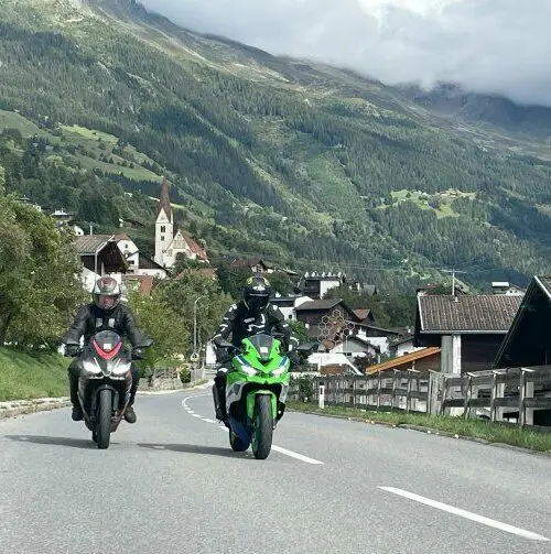 Motorrijders op een weg door een bergdorp in de Alpen
