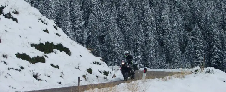 Motorrijder rijdt door besneeuwde bergen tijdens een winterse rit, motorrijden in de winter met THAT Motorreizen