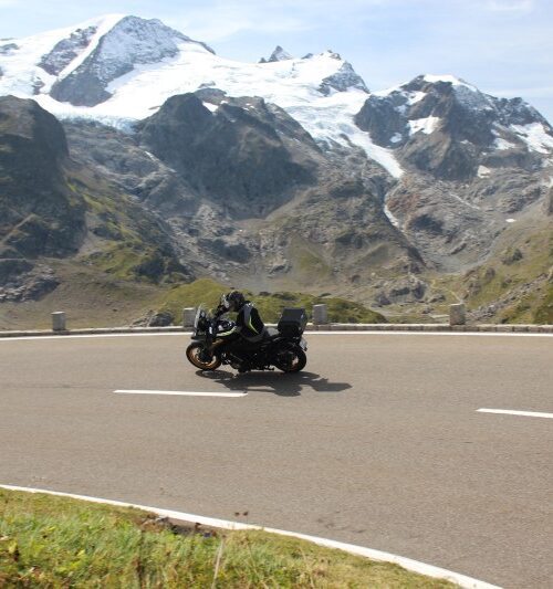 Motorrijders op een bergweg met besneeuwde Alpen