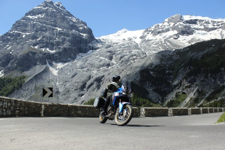 Motorrijder voor een gletsjer en besneeuwde Alpen