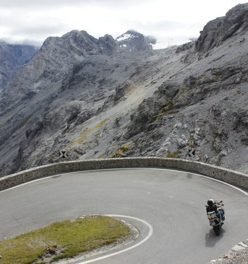 Motorrijder in een haarspeldbocht door de Dolomieten in Zuid-Tirol, Italië